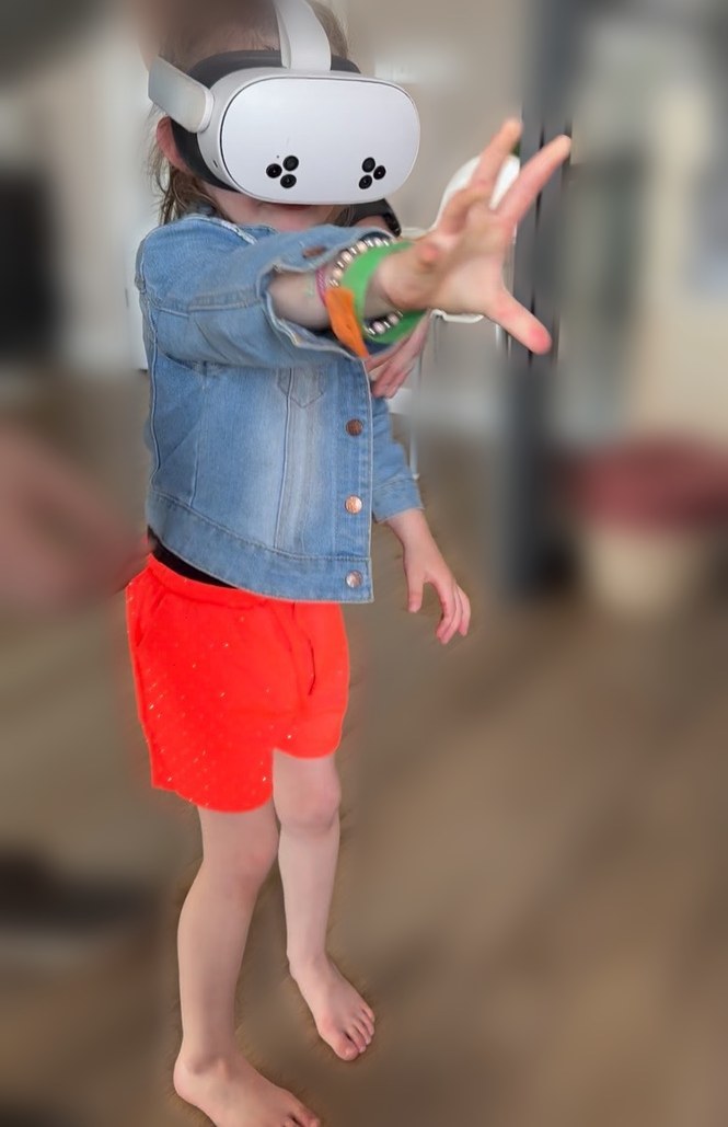 Kind met VR-bril steekt haar hand uit om iets in de virtuele wereld aan te raken